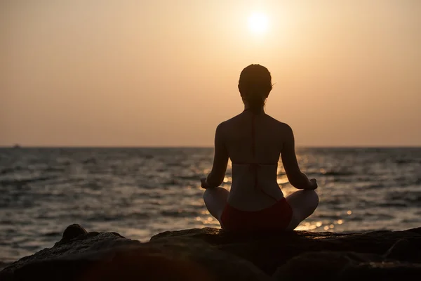 Silueta de mujer que medita en el mar al atardecer — Foto de Stock