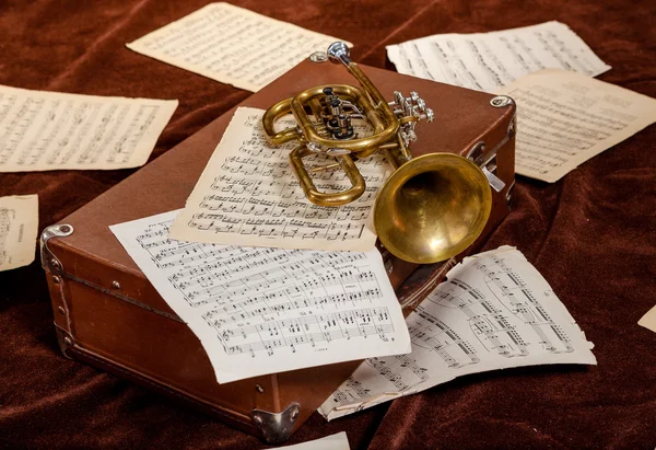 Vintage trumpet is lying between paper sheets with notes Royalty Free Stock Photos