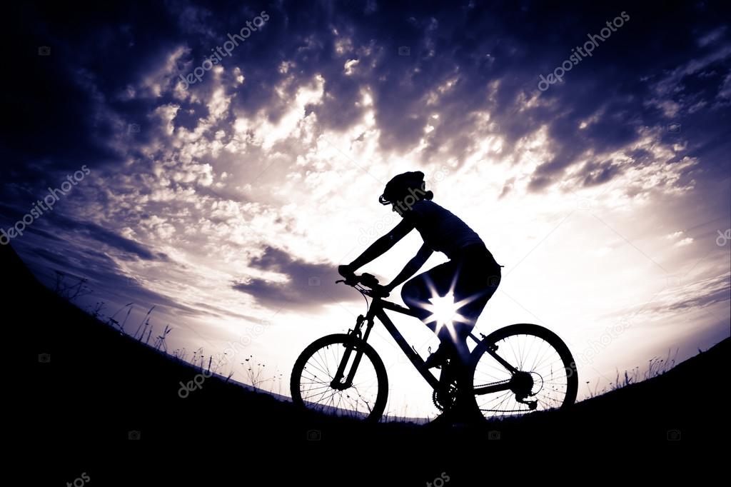 Biker-girl at the sunset on the meadow
