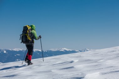 Uzun yürüyüşe çıkan kimse güneşli kış dağlarda