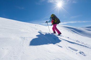 Uzun yürüyüşe çıkan kimse güneşli gün boyunca kış dağlarda