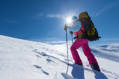 Uzun yürüyüşe çıkan kimse güneşli gün boyunca kış dağlarda