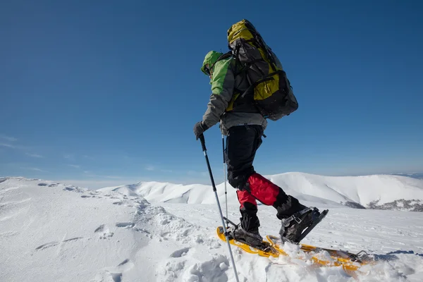 Turista na sněžnicích v zimních horách během slunečného dne — Stock fotografie
