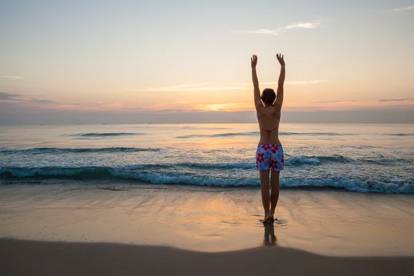 Vrouw begroet zon de kust tijdens zonsopgang — Stockfoto