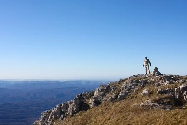 Senderista está de pie en la cima de la montaña en las montañas de Crimea contra —  Fotos de Stock