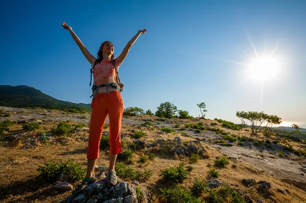 Glad kvinna på soluppgången i bergen — Stockfoto