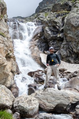 Uzun yürüyüşe çıkan kimse Kafkasya dağlarında Bezeng şelale yanında duruyor