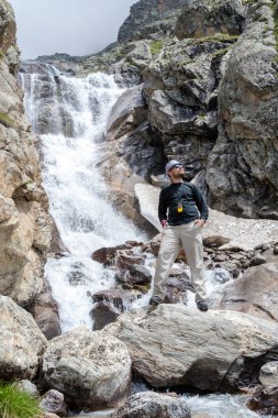 Uzun yürüyüşe çıkan kimse Kafkasya dağlarında Bezeng şelale yanında duruyor