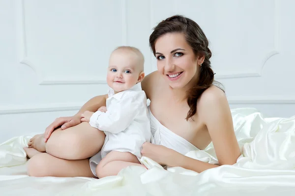 Família feliz. Mãe e seu filho bebê brincando e sorrindo na cama — Fotografia de Stock