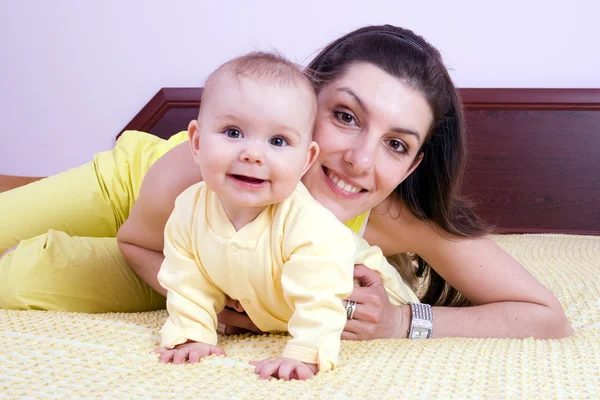Matka a dítě hrát na postel — Stock fotografie