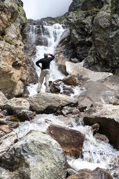 Randonneur est debout près de la cascade dans les montagnes du Caucase à Bezeng — Photo