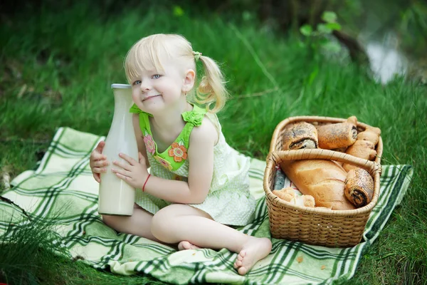 Flickan har picknick på sjön med mjölk och bullar — Stockfoto