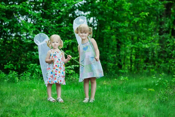 Девушки с сеткой бабочки веселятся на поле — стоковое фото