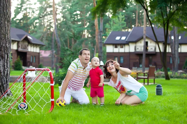 Маленький хлопчик грає у футбол з батьками в парку — стокове фото
