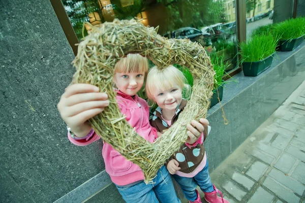 Två flickor titta igenom inredda hjärtat in i kameran — Stockfoto