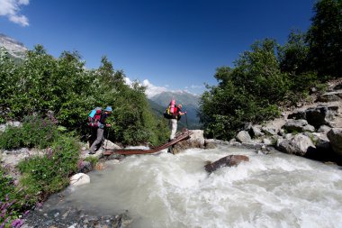 Uzun yürüyüşe çıkan kimse Kafkasya dağlarında dağ nehir geçiyor