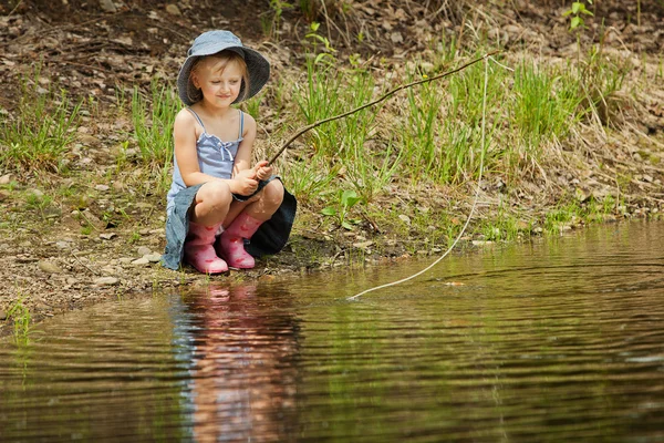 Liten flicka fiske på sjön i skogen — Stockfoto