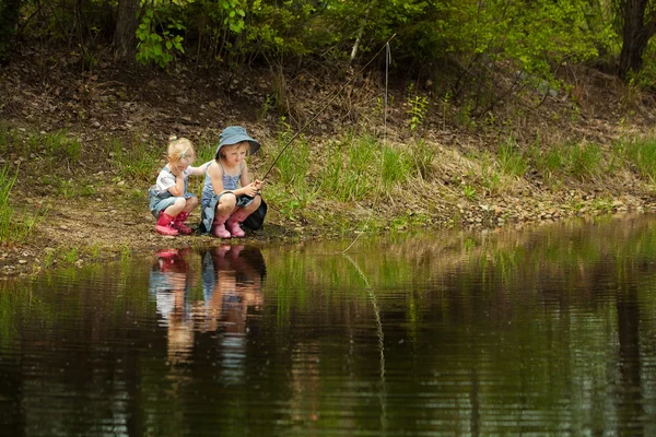 Kleine meisjes zijn vissen op lake in bos — Stockfoto