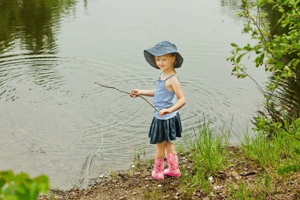 Liten flicka fiske på sjön i skogen — Stockfoto