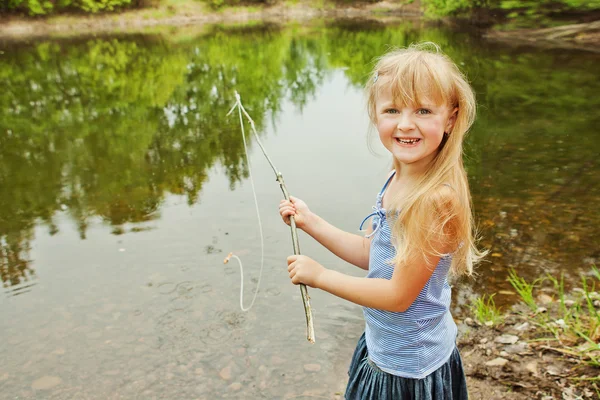 Маленька дівчинка рибалить на озері в лісі — стокове фото