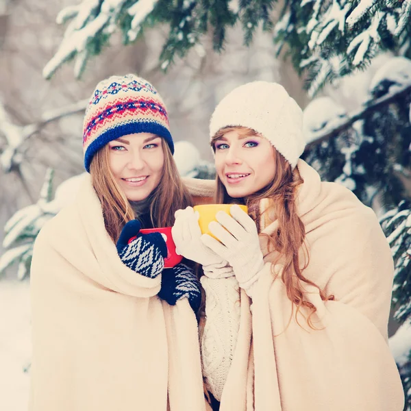 Deux jeunes femmes avec des tasses colorées boire du thé en plein air et smil — Photo