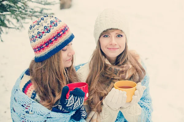 Duas jovens mulheres com copos coloridos bebendo chá ao ar livre e smil — Fotografia de Stock
