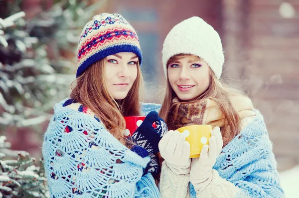 Twee jonge vrouwen met kleurrijke bekers drinken thee buiten en smil — Stockfoto