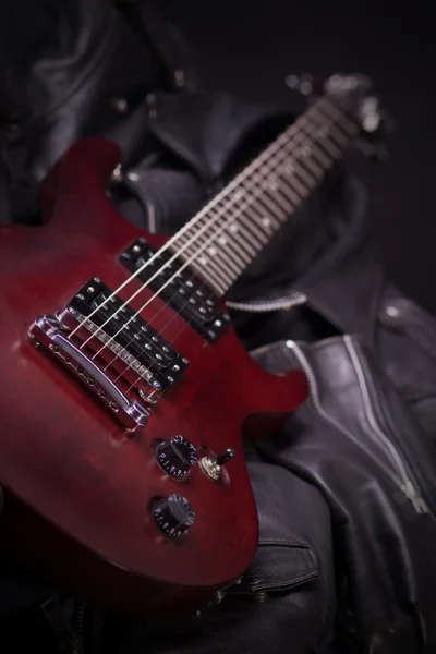Guitarra elétrica deitada em jaquetas de couro preto — Fotografia de Stock