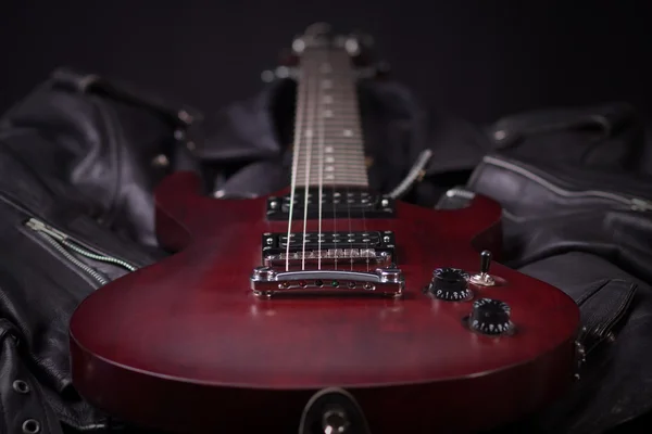 Guitarra elétrica deitada em jaquetas de couro preto — Fotografia de Stock