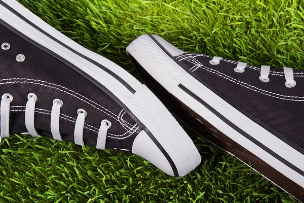 Пара черных кроссовок на зеленой траве — стоковое фото