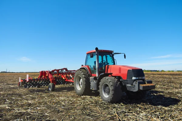 Červený traktor v poli — Stock fotografie