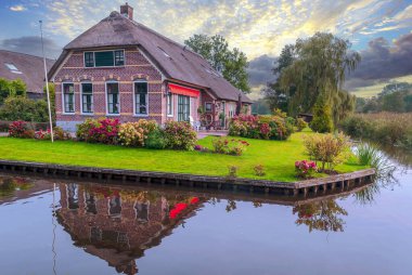 Giethoorn, bulutlu bir günde kanalları ve kırsal evleri olan Hollanda köyü.