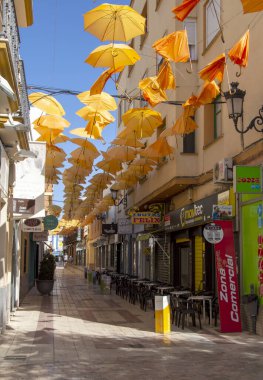 Valdepeas, İspanya Ağustos 2021. İspanyol şehrinin Comercial caddesi Ciudad Real 'de. Güneş için gökyüzünde şemsiyeli dükkanları görebilirsin.