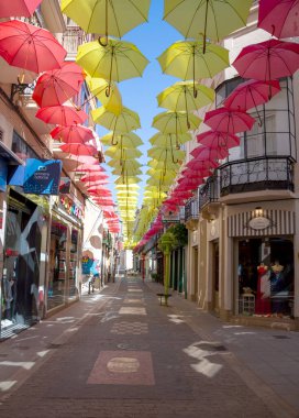 Valdepeas, İspanya Ağustos 2021. İspanyol şehrinin Comercial caddesi Ciudad Real 'de. Güneş için gökyüzünde şemsiyeli dükkanları görebilirsin.