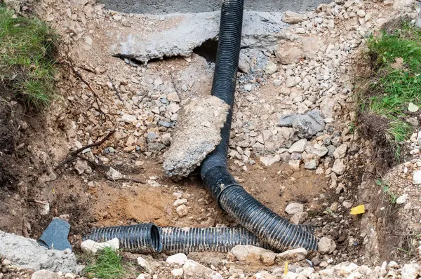 a ditch hole at a construction site with black flexible sewage pipes