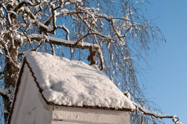 Kışın güneşli bir günde karla kaplı bir yol kenarı tapınağının çatısı.