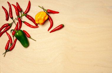 Ahşap arka planda farklı renkte ve şekillerde kırmızı biber.