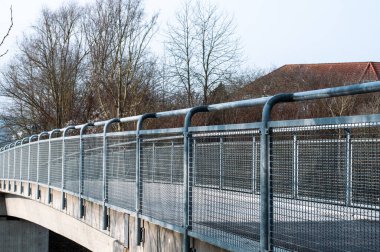 Bir şehrin caddesindeki yaya köprüsünün metal tırabzanının yanında.