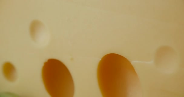 Κοντινό μέρος του Medium hard cheese head edam gouda παρμεζάνα σε ξύλινη σανίδα, με ξηρούς καρπούς και σταφύλια ροτάζ στο πιάτο. — Αρχείο Βίντεο