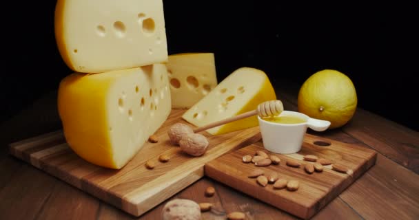 Medium hard cheese head edam gouda parmesan on wooden board, with nuts and honey. Slide shot. — Stock Video