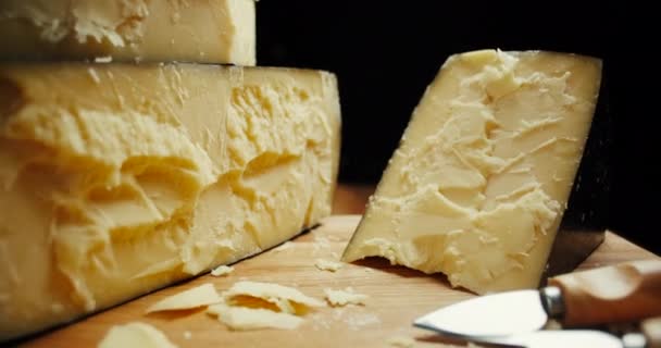 Μεσαία κεφαλή σκληρού τυριού παρμεζάνα σε ξύλινη σανίδα, με μαχαίρια παρμεζάνας τυριού. Τραβηγμένο. — Αρχείο Βίντεο