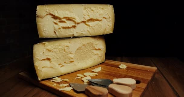 Cabeza de queso medio duro parmesano sobre tabla de madera, con cuchillos de queso parmesano. Diapositiva tiro. — Vídeos de Stock