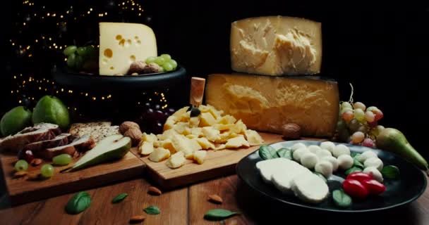 木製の背景に異なる種類のチーズの盛り合わせ。チーズの背景。スライドショット. — ストック動画