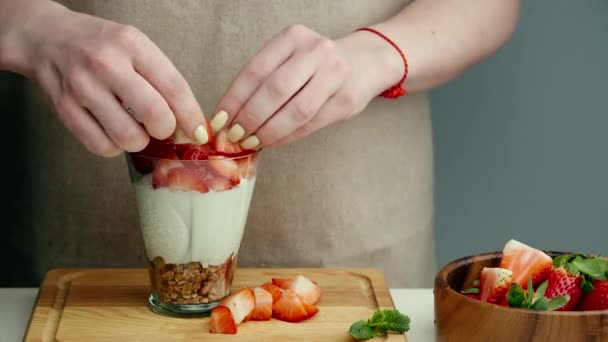 Mains féminines préparant le yaourt à la fraise pour une bonne digestion, le fonctionnement du tractus gastro-intestinal. Baies d'été, noix, fruits, produits laitiers sur la table. Concept d'alimentation saine. — Video
