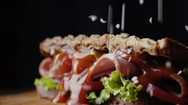 Closeup přidat sezamová semínka na sendvič se šunkou a zeleninou. — Stock video