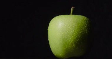 Yeşil ıslak elma, koyu bir arka planda asılı duruyor, izole..