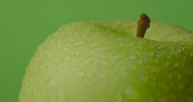 Yeşil arkaplanda asılı yeşil ıslak elma dönüşleri, izole.