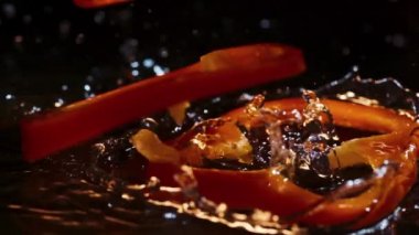 Dilimler halinde portakal dolma biber kahverengi ahşap tahtaya su damlalarıyla düşer.