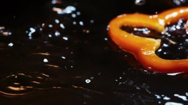 Dilimler halinde portakal dolma biber kahverengi ahşap tahtaya su damlalarıyla düşer.