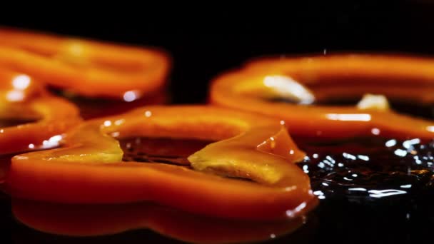 Κομμάτια orandge bell pepper πέφτουν σε καφέ ξύλινο πίνακα με σταγόνες νερού — Αρχείο Βίντεο